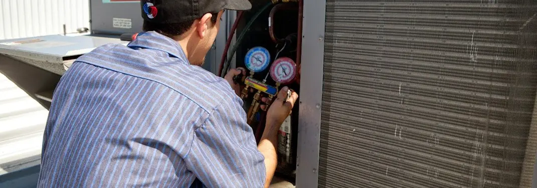 HVAC technician servicing a condenser unit in Polson